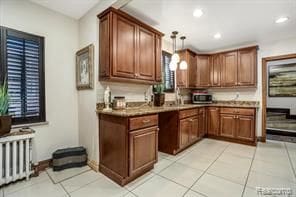 kitchen featuring radiator heating unit, sink, decorative light fixtures, and light tile patterned flooring