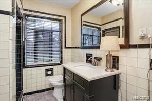 bathroom with vanity, toilet, and tile walls