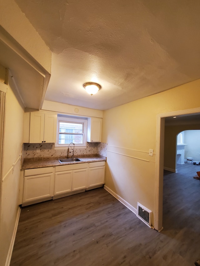 kitchen with white cabinetry, sink, dark wood-type flooring, backsplash, and a textured ceiling