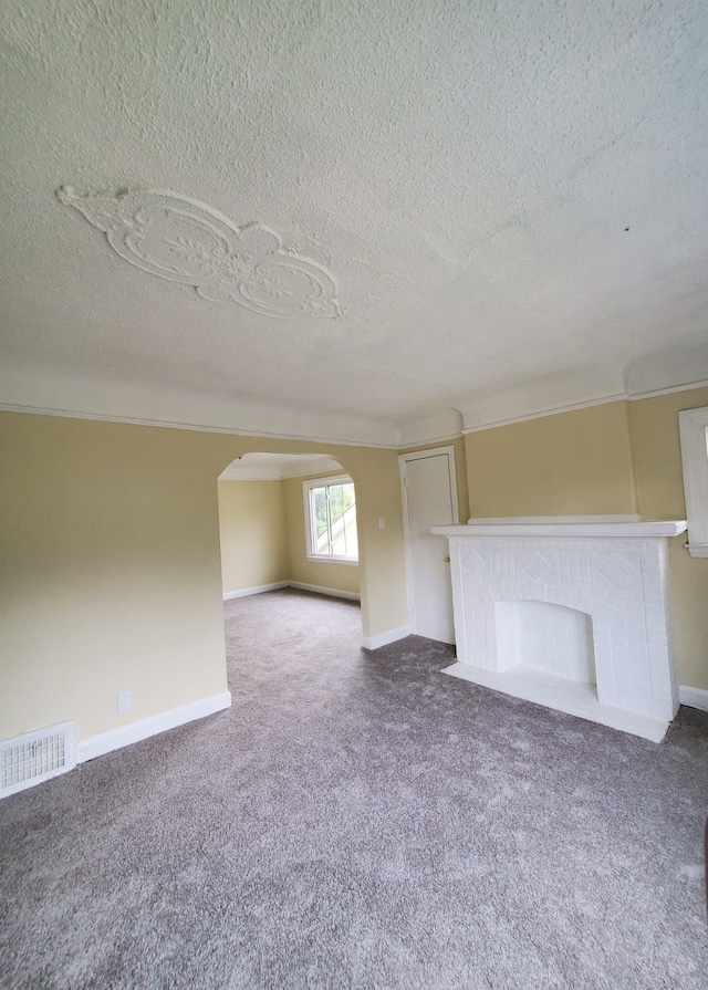 unfurnished living room featuring carpet flooring, a fireplace, and a textured ceiling