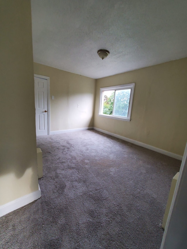 unfurnished room with dark carpet and a textured ceiling