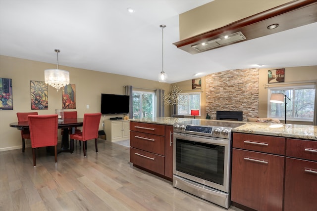 kitchen with light stone counters, decorative light fixtures, vaulted ceiling, electric range, and light hardwood / wood-style floors