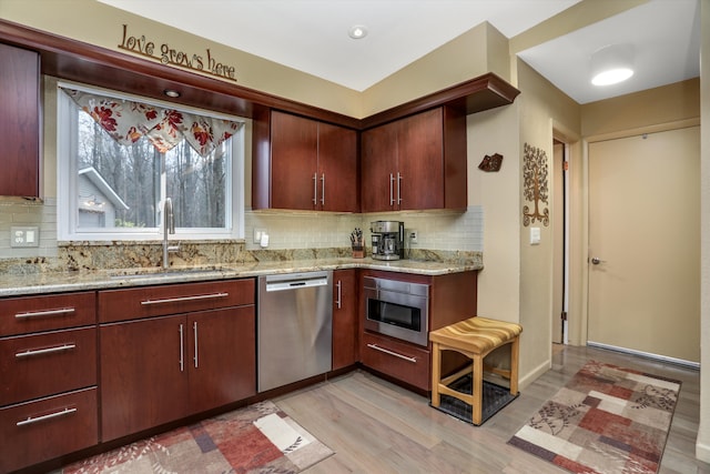 kitchen with sink, backsplash, stainless steel dishwasher, light hardwood / wood-style floors, and light stone countertops