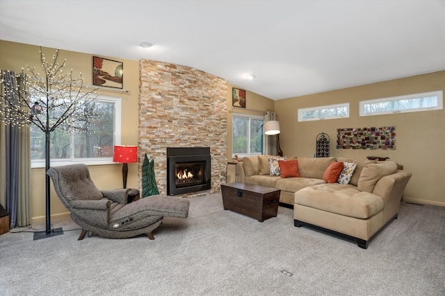 living room with lofted ceiling, a stone fireplace, and carpet