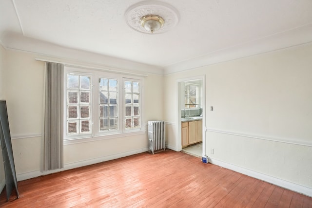 empty room with radiator heating unit and light hardwood / wood-style flooring