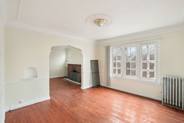 interior space with radiator heating unit, hardwood / wood-style flooring, and a fireplace