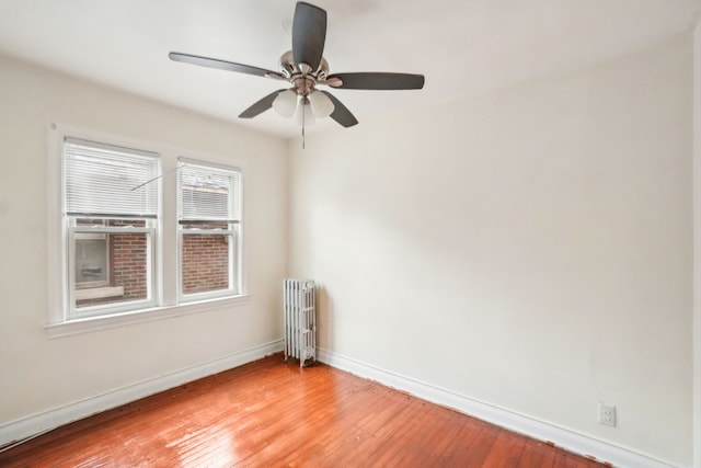 spare room with radiator, ceiling fan, and hardwood / wood-style flooring