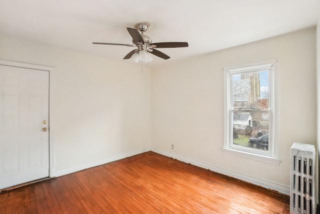 unfurnished room with ceiling fan, radiator heating unit, and hardwood / wood-style flooring