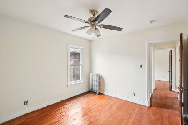 unfurnished room featuring ceiling fan, hardwood / wood-style floors, and radiator