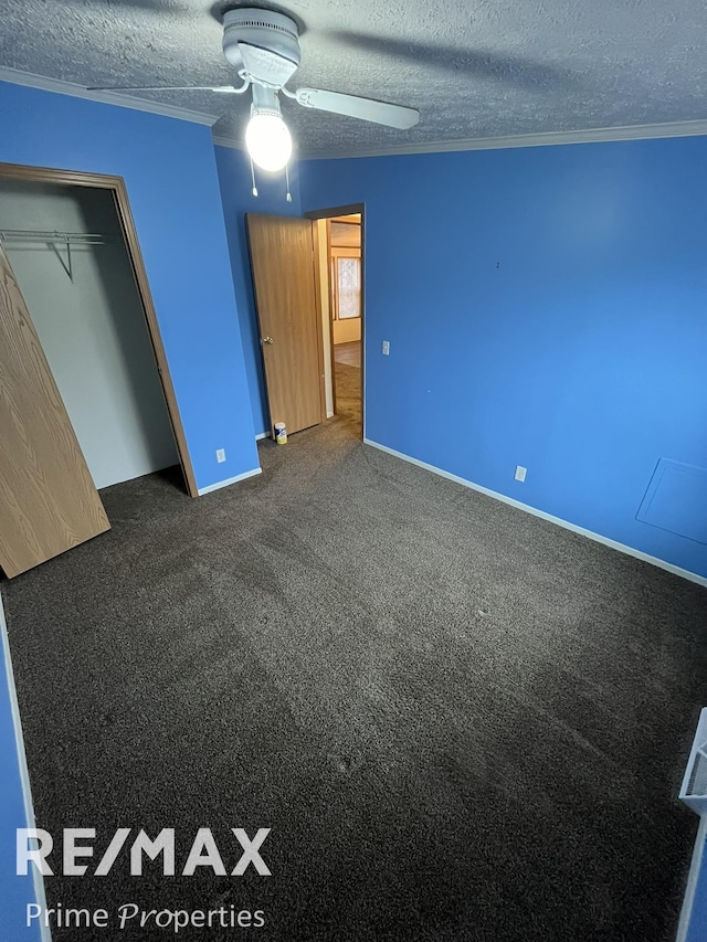 unfurnished bedroom with dark colored carpet, crown molding, ceiling fan, and a textured ceiling