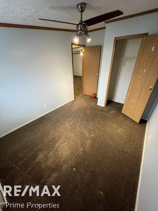 unfurnished bedroom with a textured ceiling, dark carpet, and a closet