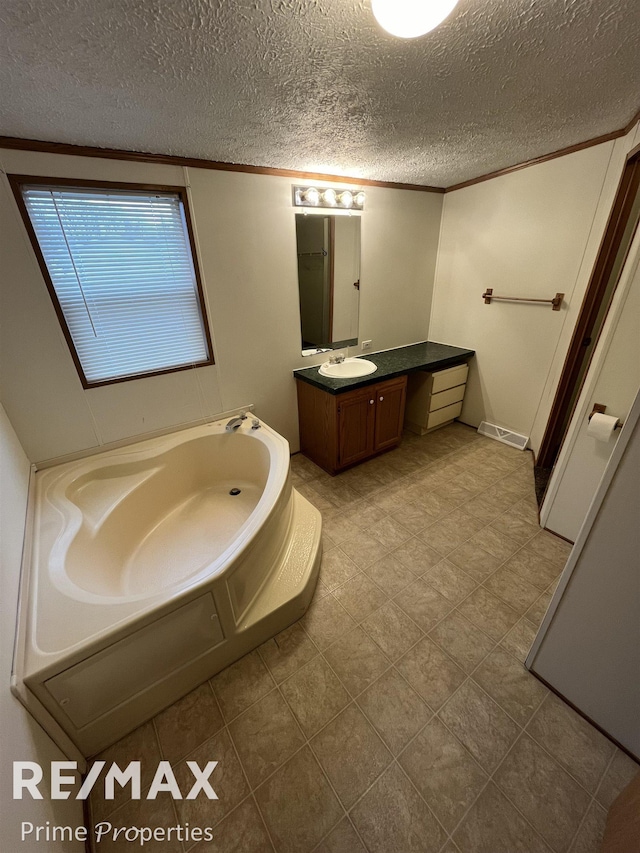 bathroom with vanity, crown molding, a textured ceiling, and a bathing tub