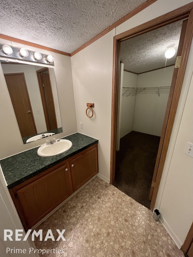 bathroom featuring vanity, ornamental molding, and a textured ceiling