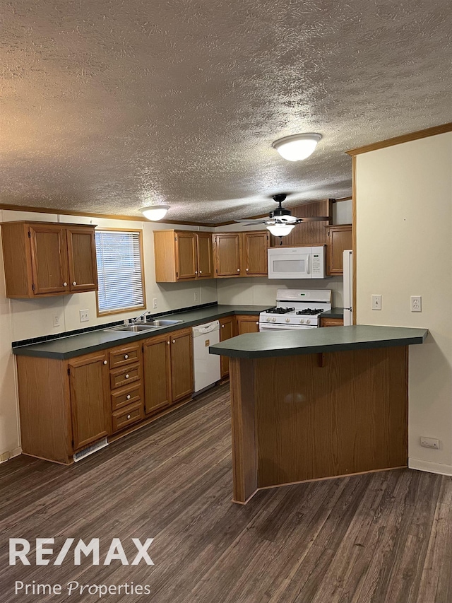 kitchen with dark hardwood / wood-style flooring, sink, white appliances, and kitchen peninsula