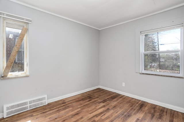 empty room featuring wood-type flooring and ornamental molding