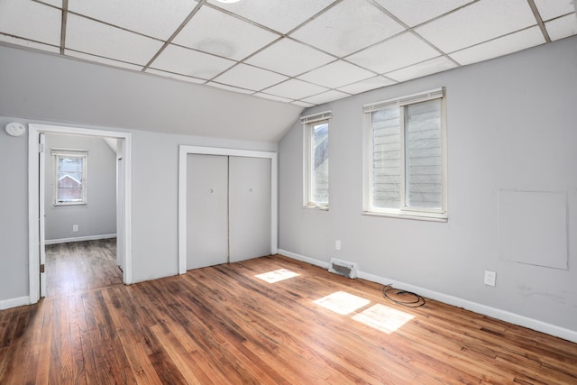 unfurnished bedroom featuring multiple windows, hardwood / wood-style floors, a paneled ceiling, and a closet