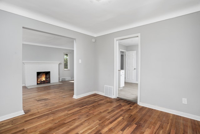 unfurnished living room with dark hardwood / wood-style floors and a brick fireplace