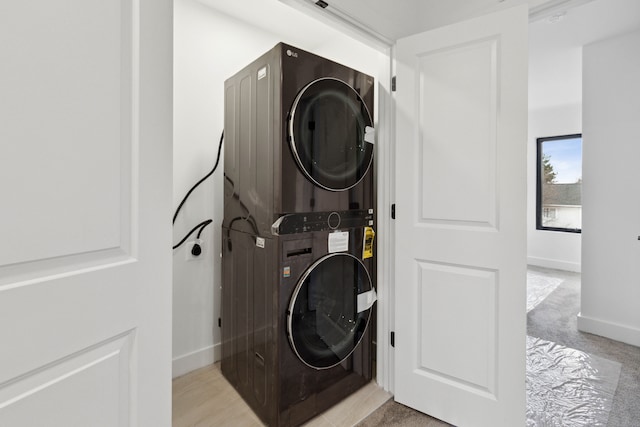 clothes washing area featuring light colored carpet and stacked washer / drying machine