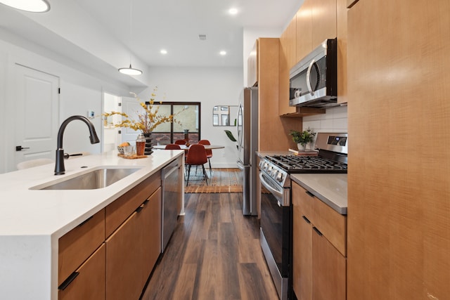 kitchen featuring backsplash, sink, appliances with stainless steel finishes, decorative light fixtures, and dark hardwood / wood-style flooring