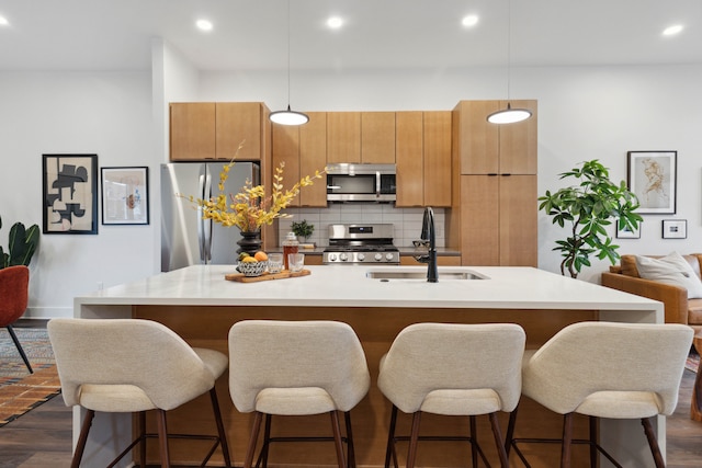 kitchen featuring backsplash, dark wood-type flooring, sink, appliances with stainless steel finishes, and decorative light fixtures