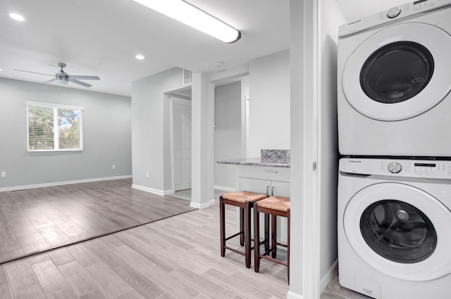 washroom with light hardwood / wood-style floors, ceiling fan, and stacked washer / drying machine