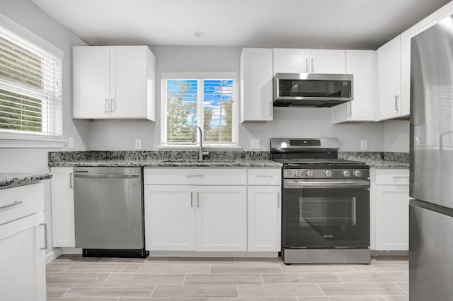 kitchen featuring white cabinets, sink, stainless steel appliances, and stone counters