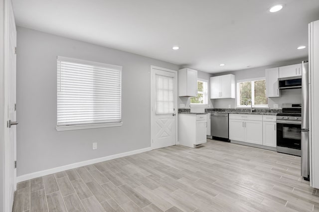 kitchen featuring white cabinets, appliances with stainless steel finishes, light wood-type flooring, and sink