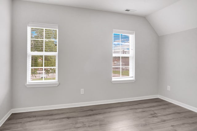 additional living space featuring hardwood / wood-style floors, a healthy amount of sunlight, and vaulted ceiling