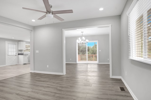 unfurnished living room with hardwood / wood-style floors and ceiling fan with notable chandelier