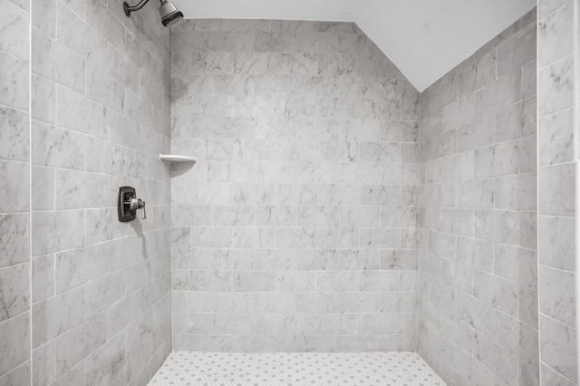 bathroom featuring tiled shower and lofted ceiling