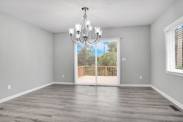 unfurnished dining area with a notable chandelier and light wood-type flooring