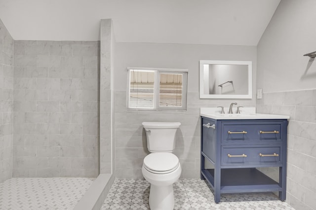 bathroom with tile patterned flooring, lofted ceiling, toilet, vanity, and tile walls