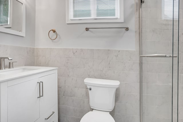 bathroom featuring vanity, toilet, and tile walls