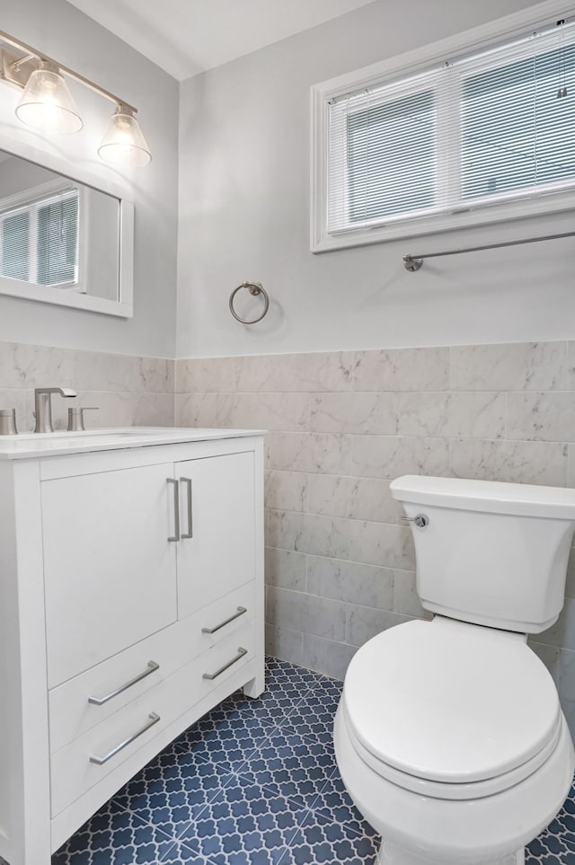 bathroom with vanity, toilet, and tile walls