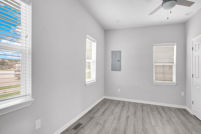 spare room featuring ceiling fan, a healthy amount of sunlight, light hardwood / wood-style floors, and electric panel