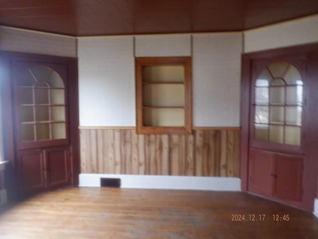 interior space with hardwood / wood-style floors and wooden walls