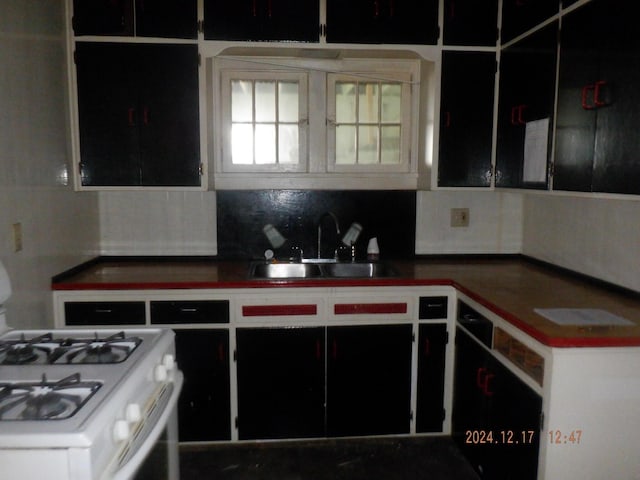 kitchen featuring tasteful backsplash, white gas stove, and sink