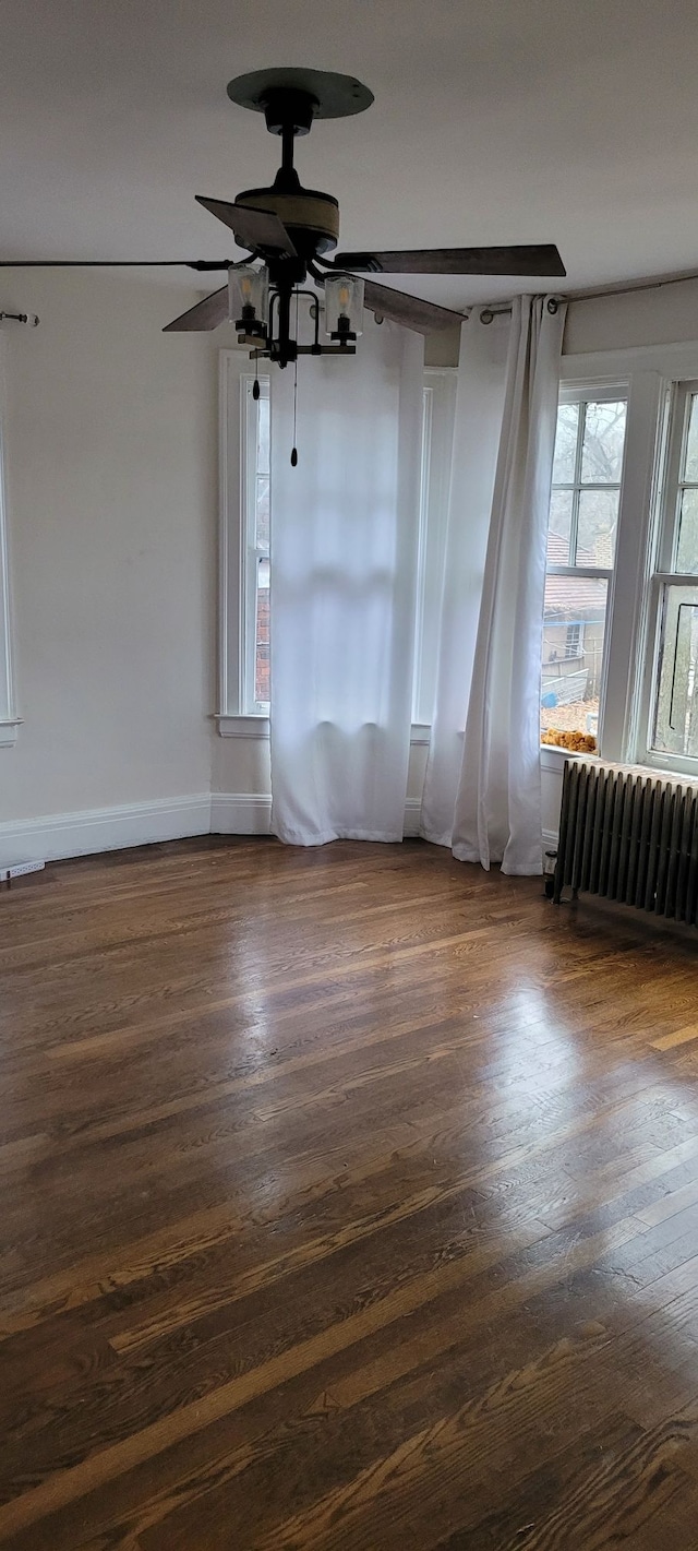 unfurnished room with ceiling fan, dark hardwood / wood-style flooring, and radiator