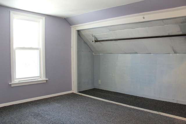 additional living space featuring vaulted ceiling and dark colored carpet