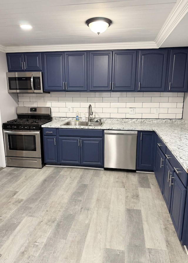 kitchen featuring blue cabinetry, sink, tasteful backsplash, appliances with stainless steel finishes, and light wood-type flooring