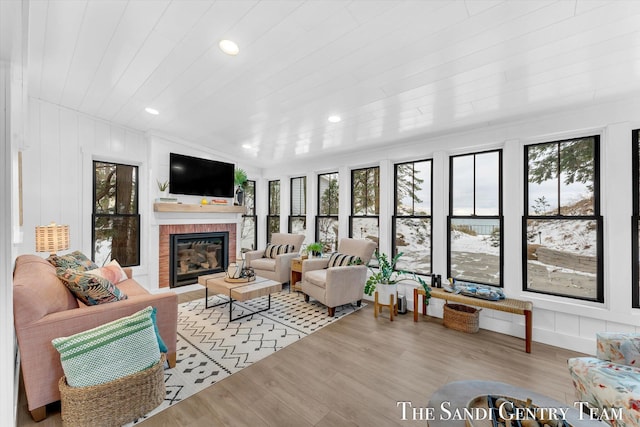 living room with a fireplace, light wood-type flooring, wood ceiling, and a healthy amount of sunlight