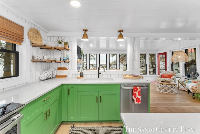 kitchen with sink, green cabinets, hanging light fixtures, and appliances with stainless steel finishes