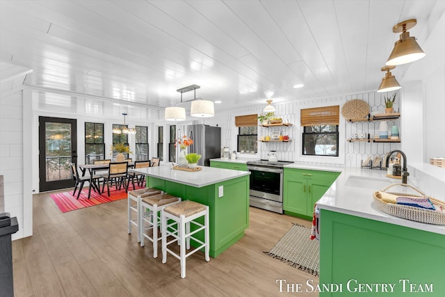 kitchen with appliances with stainless steel finishes, a kitchen bar, a kitchen island, green cabinets, and sink