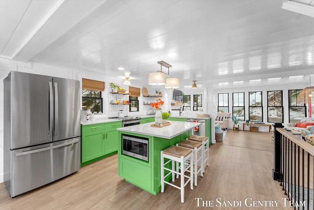 kitchen featuring a wealth of natural light, hanging light fixtures, a center island, a breakfast bar, and appliances with stainless steel finishes