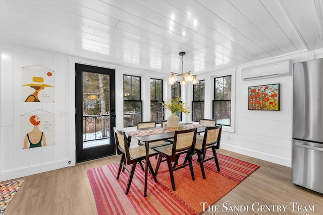 dining room with a wall unit AC, wood-type flooring, wooden ceiling, and a chandelier