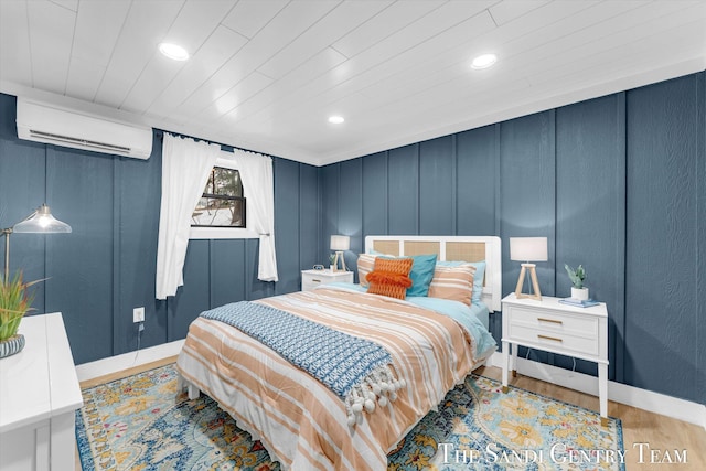 bedroom with an AC wall unit, light hardwood / wood-style flooring, and wooden ceiling