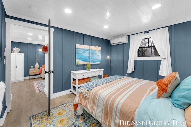 bedroom featuring a wall unit AC and light hardwood / wood-style flooring