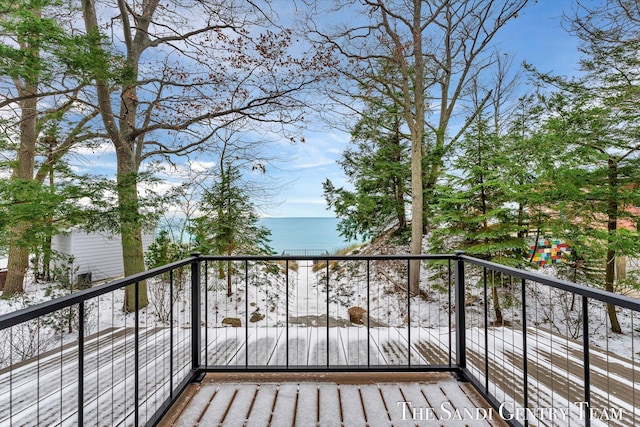 snow covered back of property with a water view