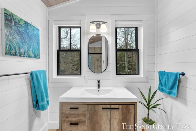 bathroom with wooden walls, a wealth of natural light, and vanity