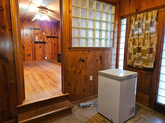 interior space featuring ceiling fan and wood walls